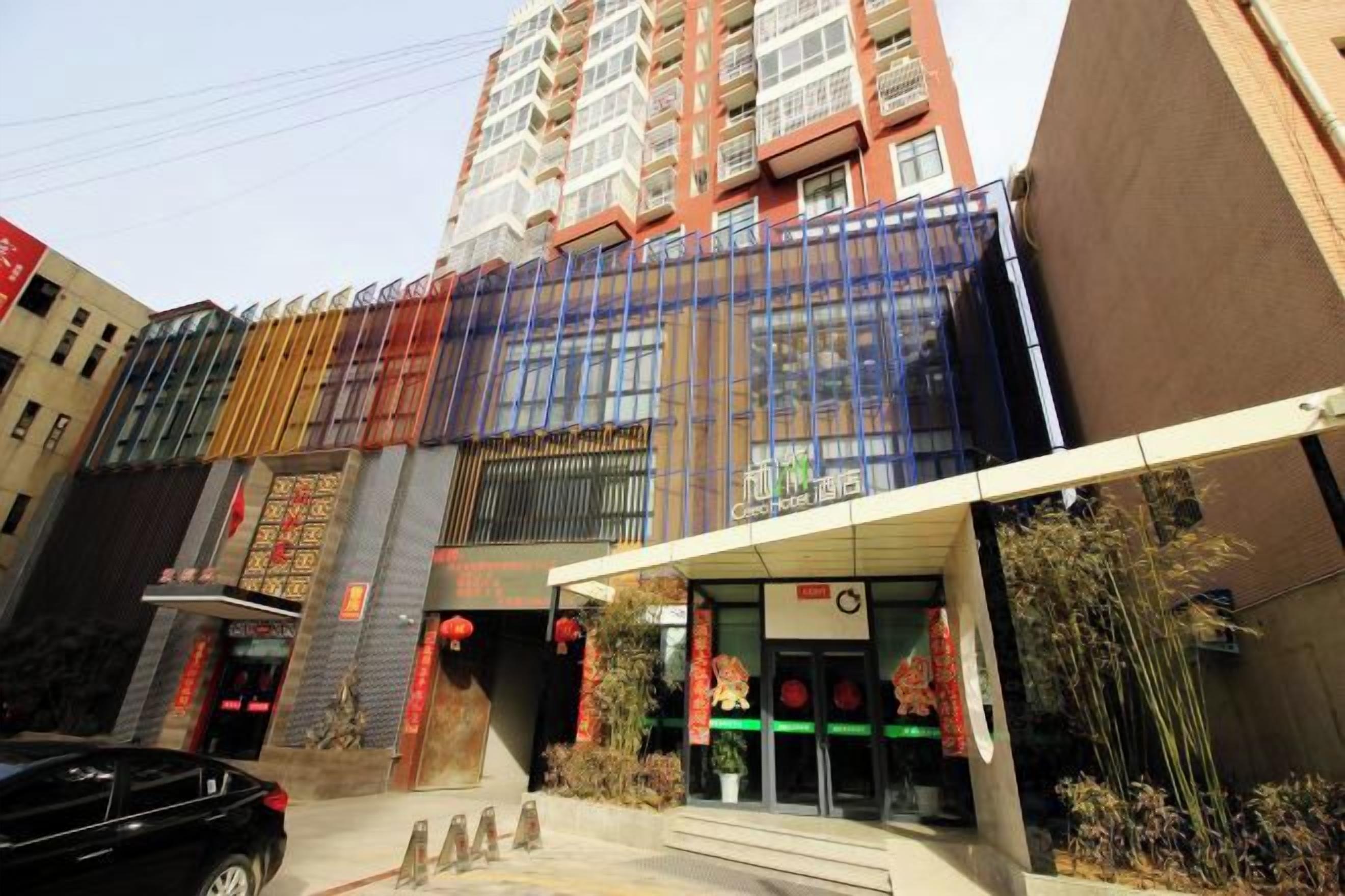 A multi-story building with a modern facade, a visible entrance, and a car parked in front.