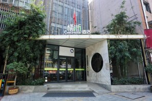 The entrance to a hotel with a modern glass facade, a covered entrance area, and a circular window. - Ceeci Hotel (Xichuan)