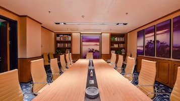 A conference room with a long table, chairs, bookshelves, and artwork on the walls.