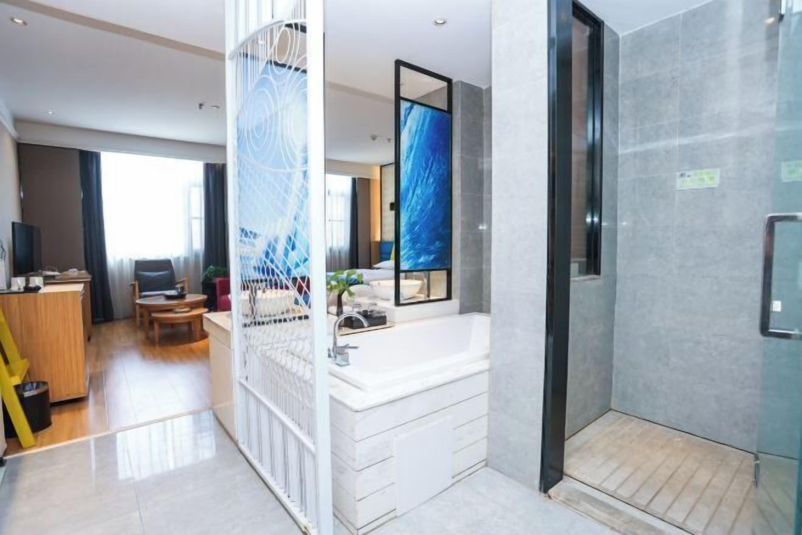 Ein modernes Hotelzimmer mit großem Fenster, eigenem Badezimmer, Essbereich und Wohnbereich.