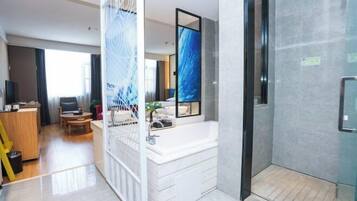 Ein modernes Hotelzimmer mit großem Fenster, eigenem Badezimmer, Essbereich und Wohnbereich.