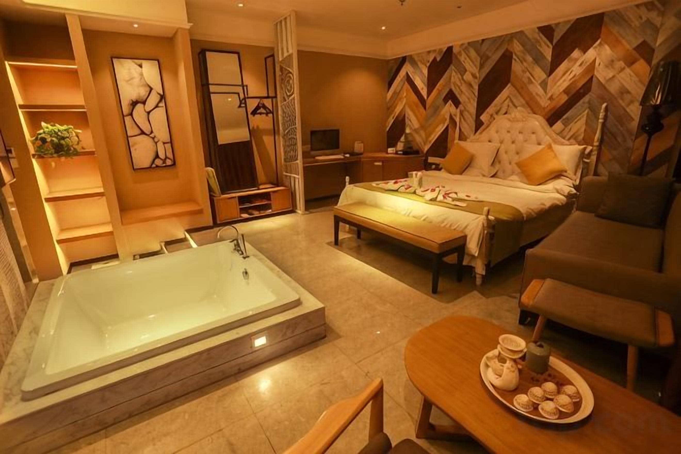 A modern bedroom with a large bathtub, a bed with a headboard, a bedside table, and a chair.