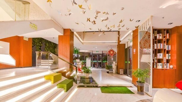 Vestíbulo de hotel con una escalera, un mostrador de recepción y una zona de estar.