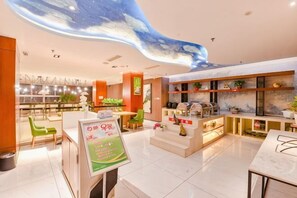 A modern hotel lobby with a central reception desk, seating areas, and a decorative ceiling. - Ceeci Hotel (Xichuan)