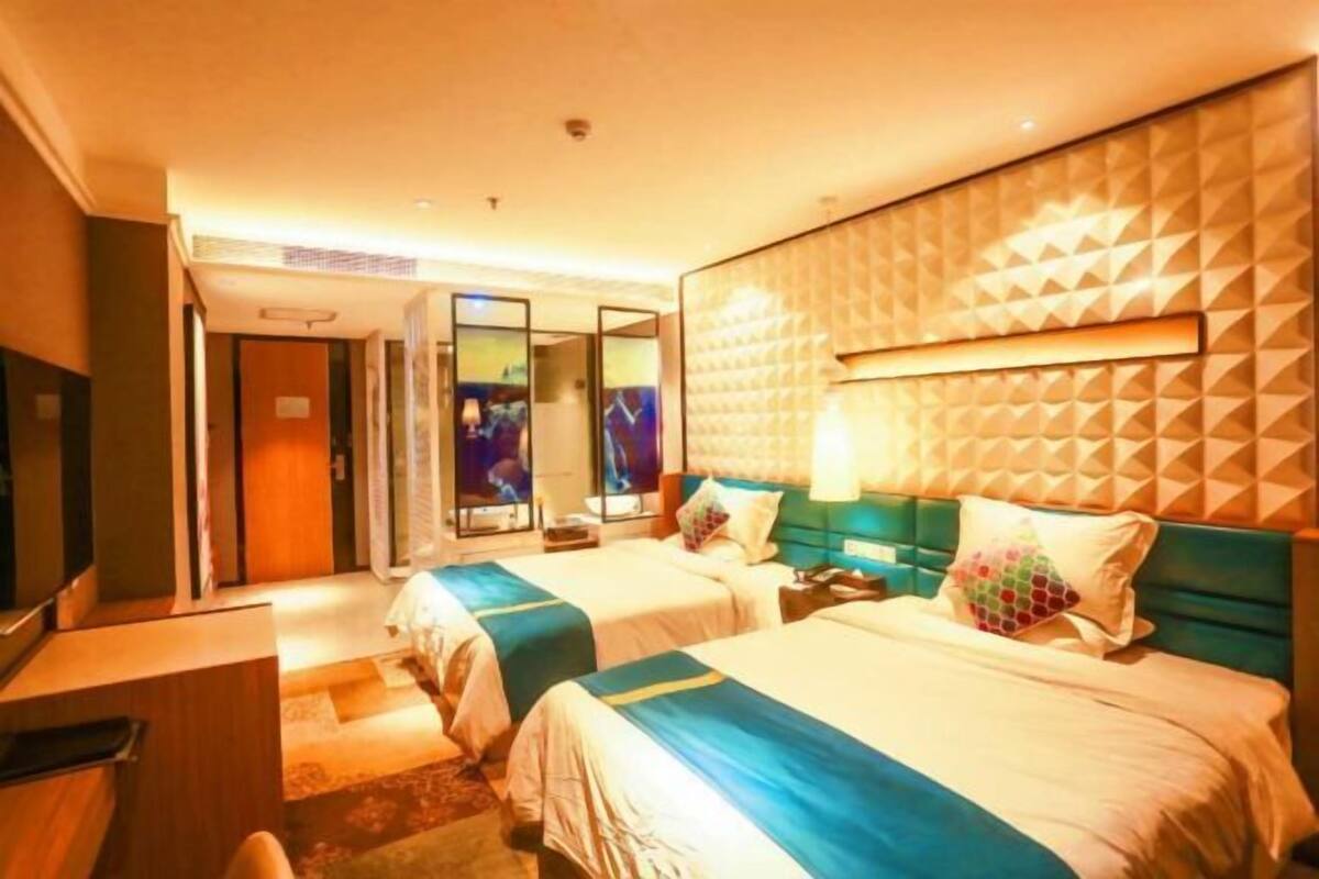 Quarto de hotel com duas camas, uma escrivaninha e um espelho.