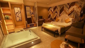 Un dormitorio amplio con una bañera grande, una cama con cabecera, un sofá y una mesa de comedor con una bandeja de pasteles.