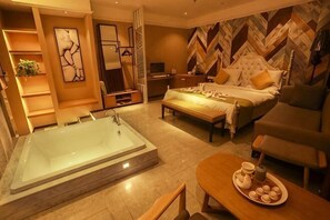 Un dormitorio amplio con una bañera grande, una cama con cabecera, un sofá y una mesa de comedor con una bandeja de pasteles.