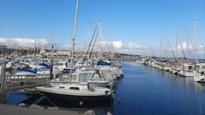 A marina with numerous boats docked, calm water, and a clear sky.