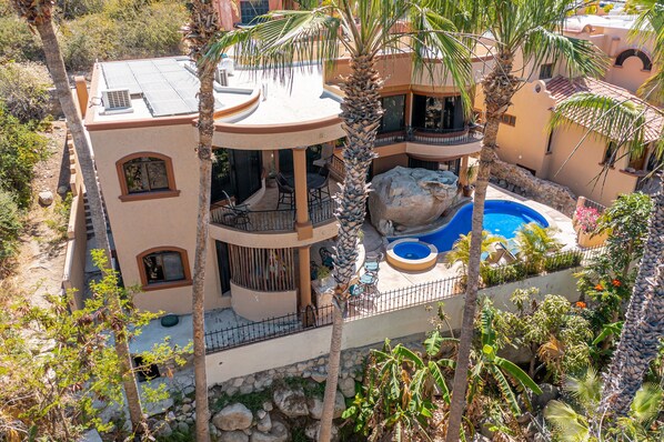 A multi-story building with a pool, balconies, and tropical landscaping.
