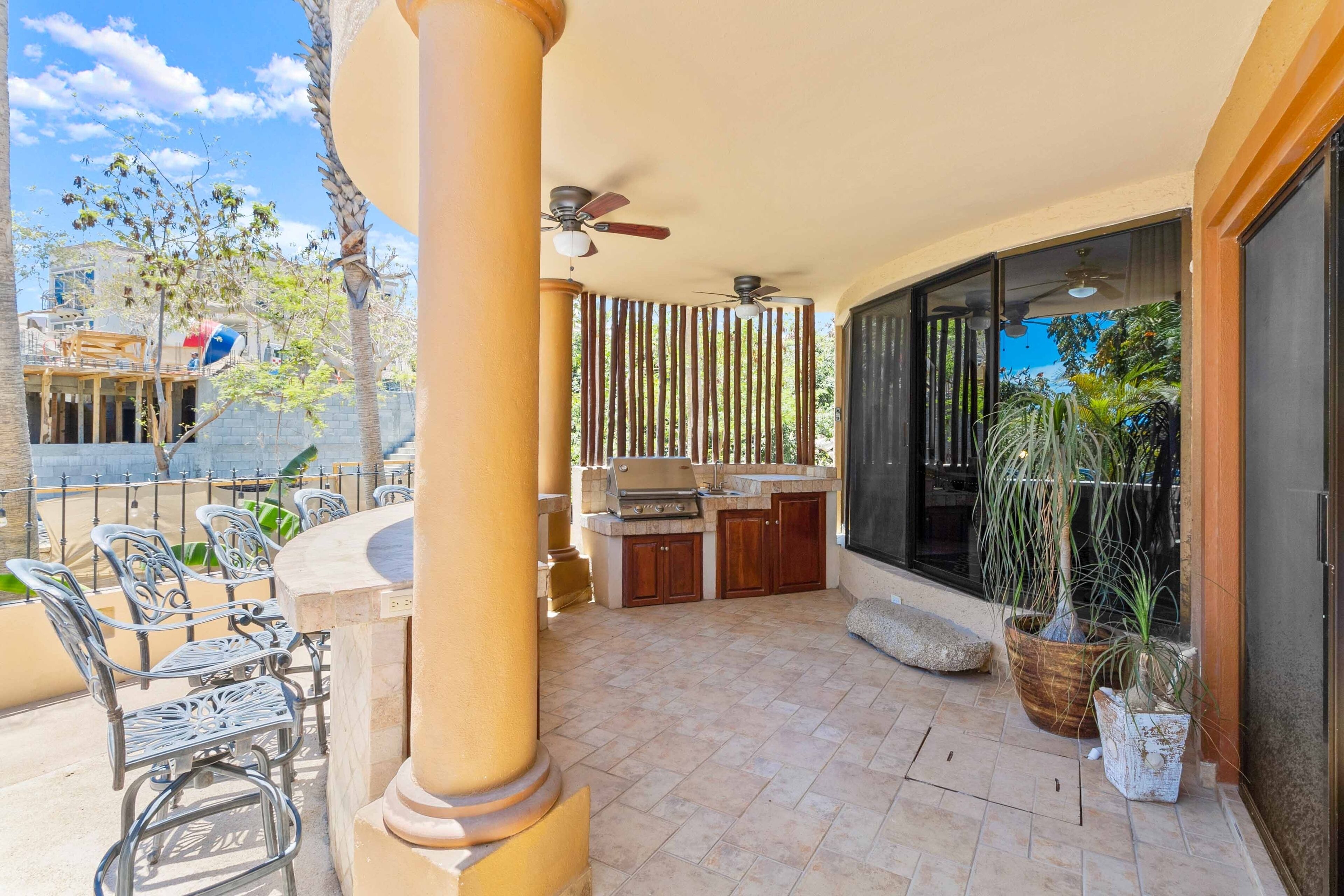 An outdoor patio with a grill, seating, and a large window.