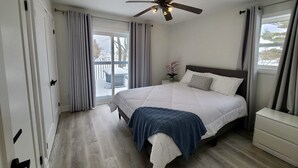 Un dormitorio con cama, mesita de noche, cómoda, ventilador de techo y vistas al exterior.