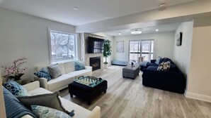 Una sala moderna con chimenea, un televisor grande y un rincón de estar acogedor.