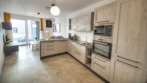 A modern kitchen with light wood cabinets, stainless steel appliances, and a dining area with a table and chairs. - Bright and modern apartment near seafront BFRA1-2 (Gzira)