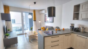 A modern kitchen with a central island, built-in cabinets, and a dining area with a table and chairs. - Bright and modern apartment near seafront BFRA1-2 (Gzira)