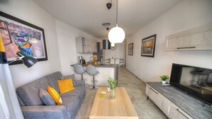 A modern living room with a grey sofa, a wooden coffee table, and a TV on a cabinet. - Bright and modern apartment near seafront BFRA1-2 (Gzira)