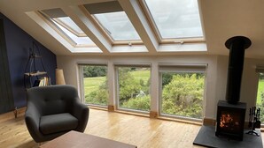 A modern living room with skylights, a fireplace, and a view of greenery.