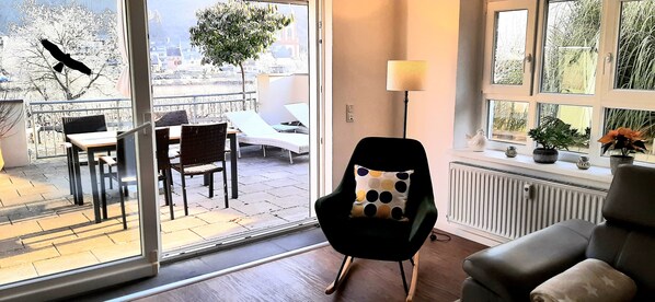 Et værelse med balkonudsigt, en stol med prikket pude, en gulvlampe og en radiator.