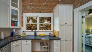 A kitchen with white cabinets, a black countertop, and a window with hanging lights.