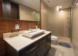 Un baño moderno con un lavamanos grande, tocador y zona de ducha.