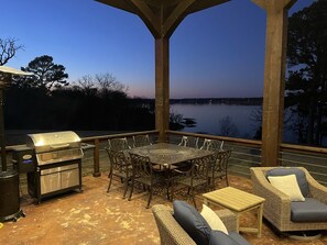An outdoor patio with a grill, dining table, and chairs, overlooking a body of water. - Grand Lake @ Stony Point Gated Resort - The Lodge, Lakehouse and 4 Cabins (Jay)