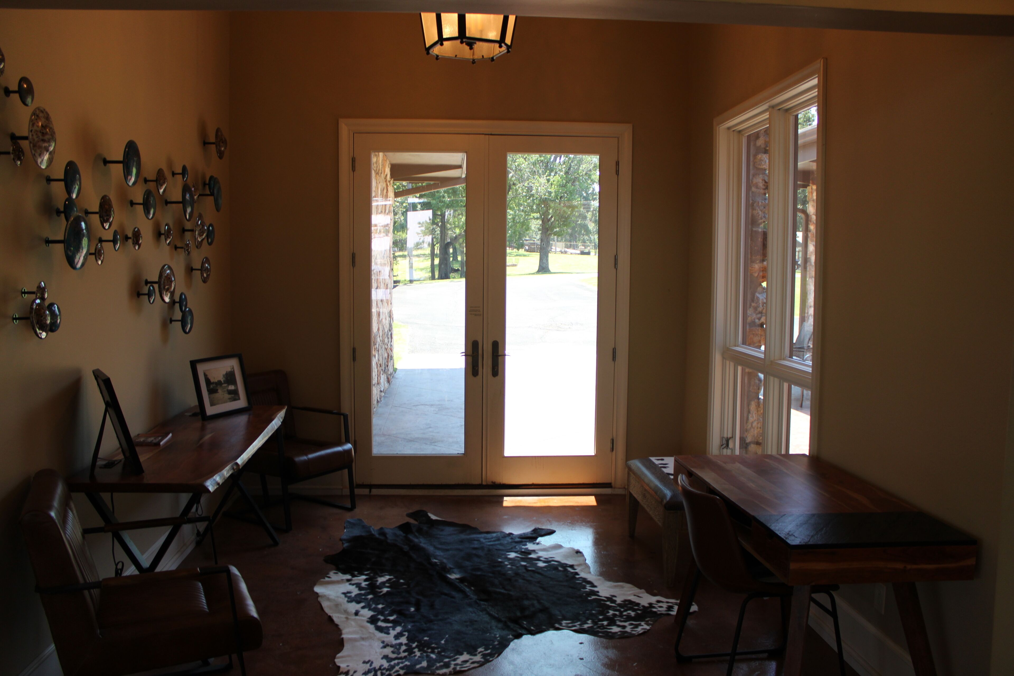 A room with a wooden table, a bench, a cowhide rug, and a wall-mounted light fixture.
