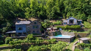Ein großes Steinhaus mit Swimmingpool, umgeben von üppiger Vegetation und einem kleineren Haus.