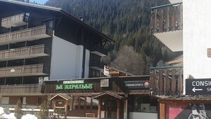Un bâtiment abritant un bar-restaurant appelé « La Ripaille », un magasin d’articles de sport et un magasin de location de matériel de ski.