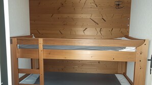 Un lit superposé en bois, doté d’une tête de lit et d’une petite étagère.