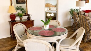 A dining area with a round glass table, wicker chairs, a central potted plant, and a large mirror on the wall. - CLEAN, CLEAN, CLEAN; Walk to pools; Golf Cart Included; NO Xtra guest fees !!! (The Villages)