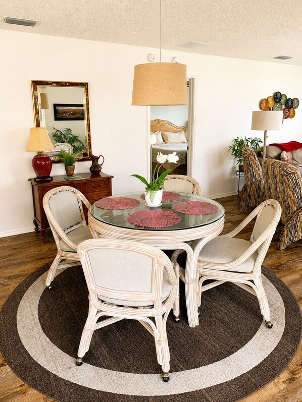 A dining area with a round glass table, wicker chairs, a central potted plant, and a large mirror on the wall. - CLEAN, CLEAN, CLEAN; Walk to pools; Golf Cart Included; NO Xtra guest fees !!! (The Villages)