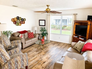 A living room with a sofa, armchairs, a coffee table, a TV stand, a ceiling fan, and a window with blinds. - CLEAN, CLEAN, CLEAN; Walk to pools; Golf Cart Included; NO Xtra guest fees !!! (The Villages)