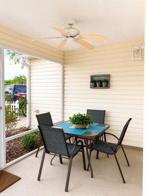 A covered patio with a table and chairs, a ceiling fan, and a small wall-mounted light fixture. - CLEAN, CLEAN, CLEAN; Walk to pools; Golf Cart Included; NO Xtra guest fees !!! (The Villages)