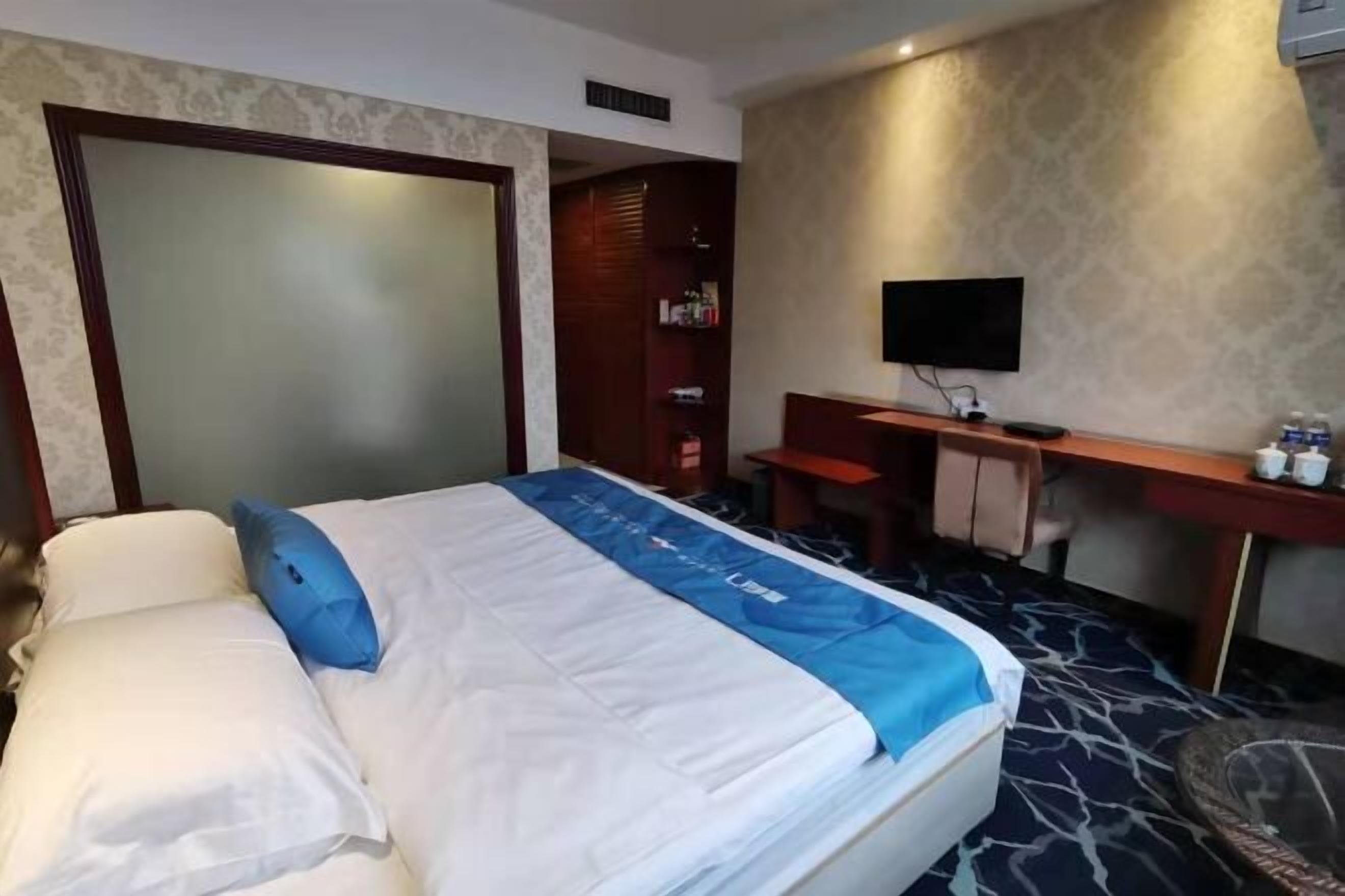 Una habitación de hotel con cama, escritorio, televisor y armario.