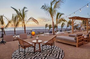 Relax in comfort with ocean views from this beachside lounge area, featuring lounge chairs and a small table.