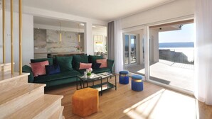 A modern living room with a green sofa, a glass coffee table, and a wooden staircase. - Villa Iva With sea View and Pool (Omis)