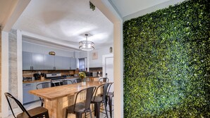 Eine moderne Küche mit einer Holzinsel, grauen Schränken und einer Wand mit grünen Blättern.