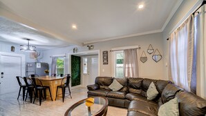 Ein Wohnzimmer mit einer Ledersofa, einem Glastisch und einem Essbereich mit Holztisch und Stühlen.