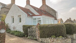 A white cottage with a red-tiled roof, a stone chimney, and a small window. - Twincote (Wooler)