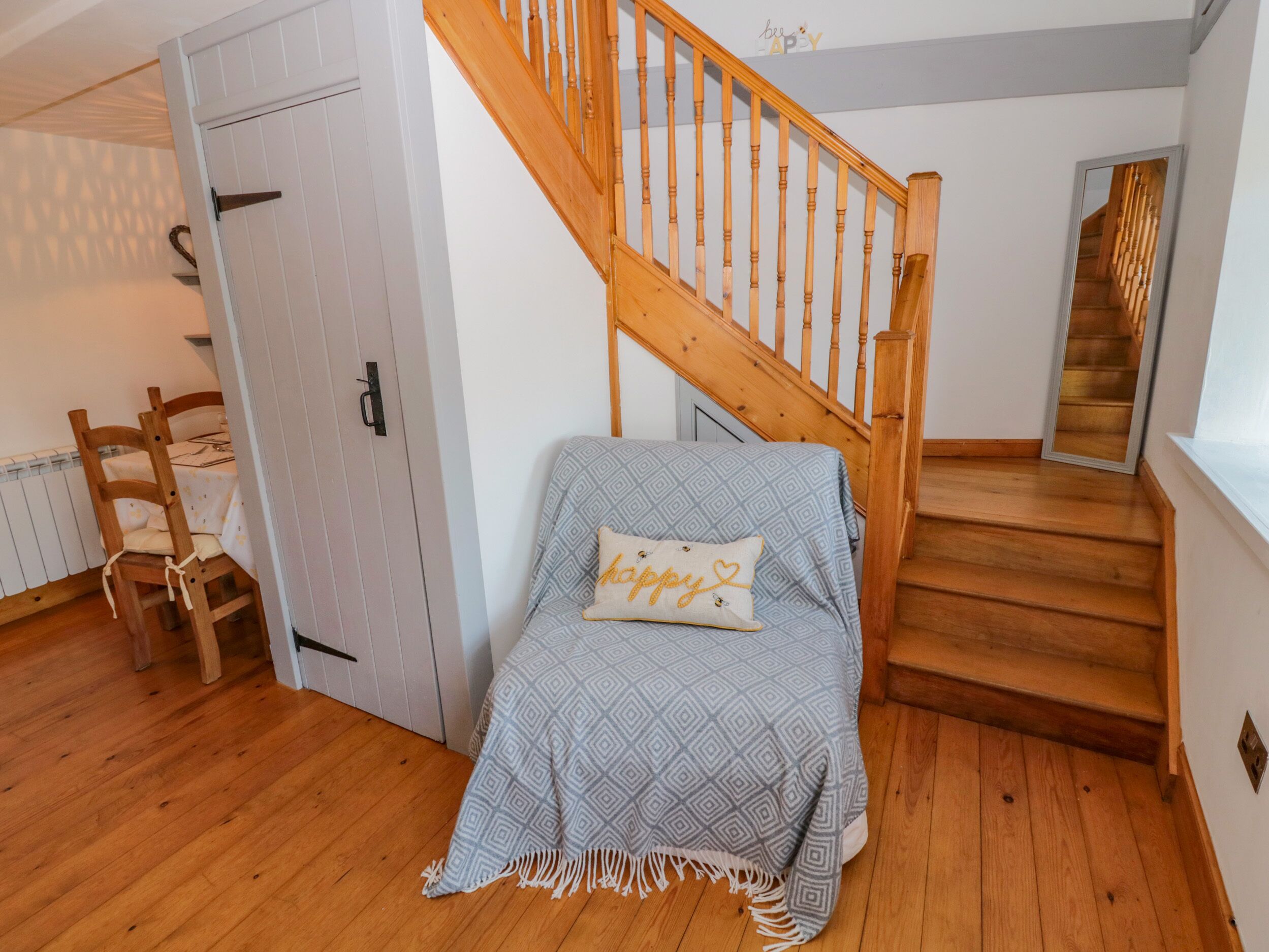 A bedroom with a bed, a wooden chair, a staircase, and a door.