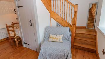 A bedroom with a bed, a wooden chair, a staircase, and a door.