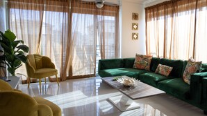 A living room with a green sofa, yellow armchair, and a coffee table. - Beautiful 2BR City Center - Renty (Santo Domingo)