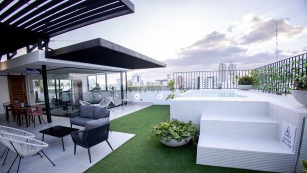 A rooftop terrace with a pool, seating area, and city views. - Beautiful 2BR City Center - Renty (Santo Domingo)