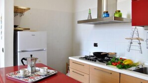 A compact kitchen with a red countertop, a stove, and a coffee maker. - Sotto Il Segno Dei Pesci by Interhome (Formia)