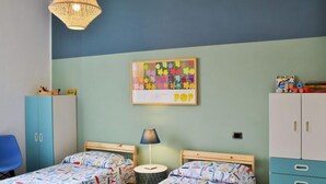A room with two beds, a blue chair, a wardrobe, a lamp, and a colorful artwork on the wall. - Sotto Il Segno Dei Pesci by Interhome (Formia)