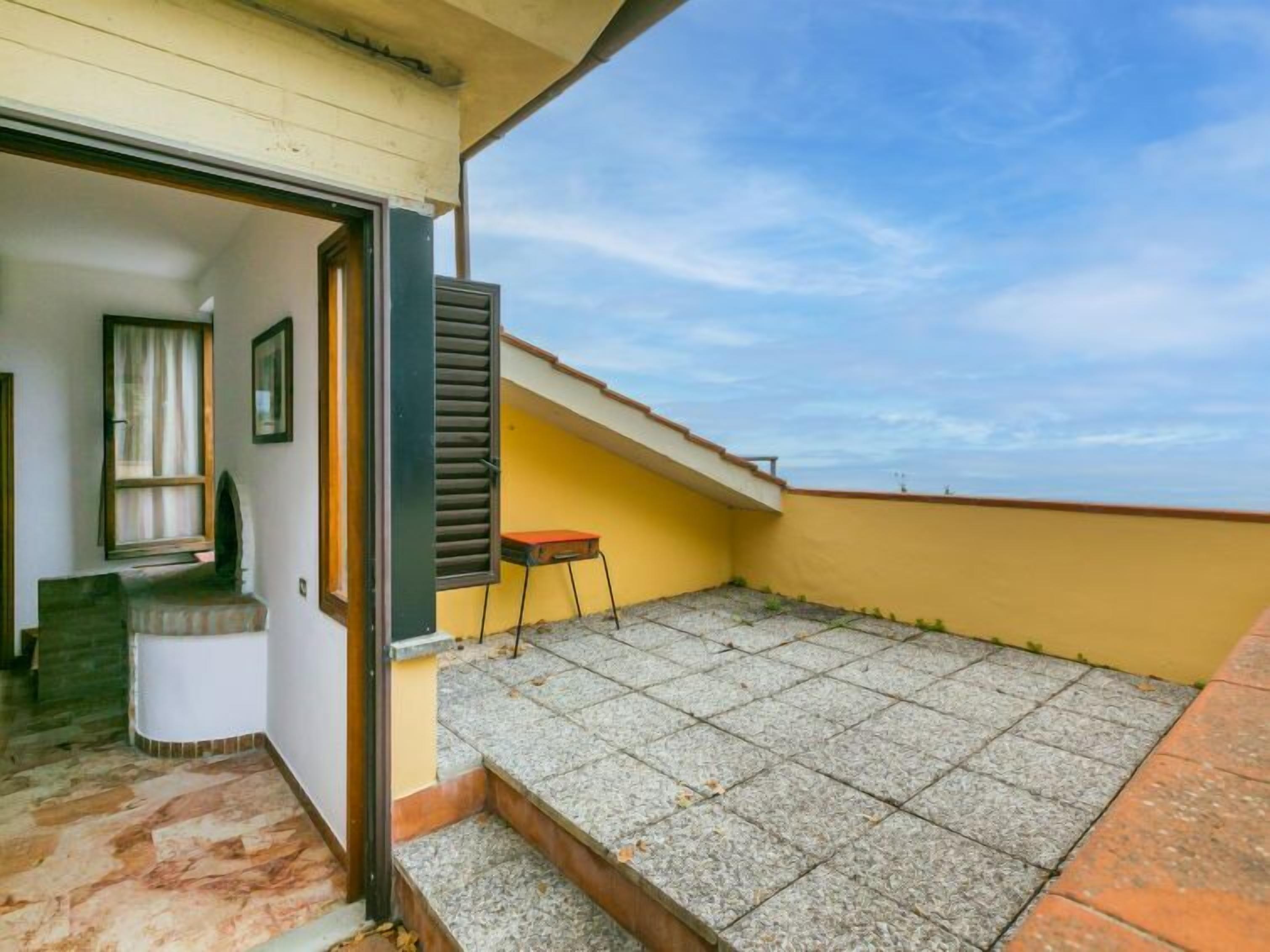 Un balcon avec un sol carrelé et une petite table.