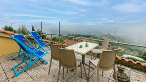 Una terraza con una mesa y sillas, con vistas a un paisaje pintoresco.