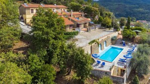 Un hotel en una ladera con piscina, varias habitaciones y vistas a las colinas circundantes.