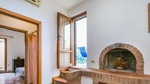 Una habitación con chimenea, ventana y escalera que lleva a otra zona.