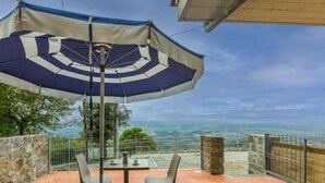Une terrasse avec une table et des chaises, protégée par un parasol à rayures, et offrant une vue panoramique.