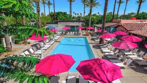 A pool area with lounge chairs and pink umbrellas, surrounded by palm trees. - The Paloma Resort (Cathedral City)